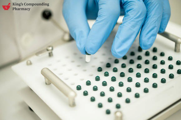 Gloved hands preparing capsules in a lab