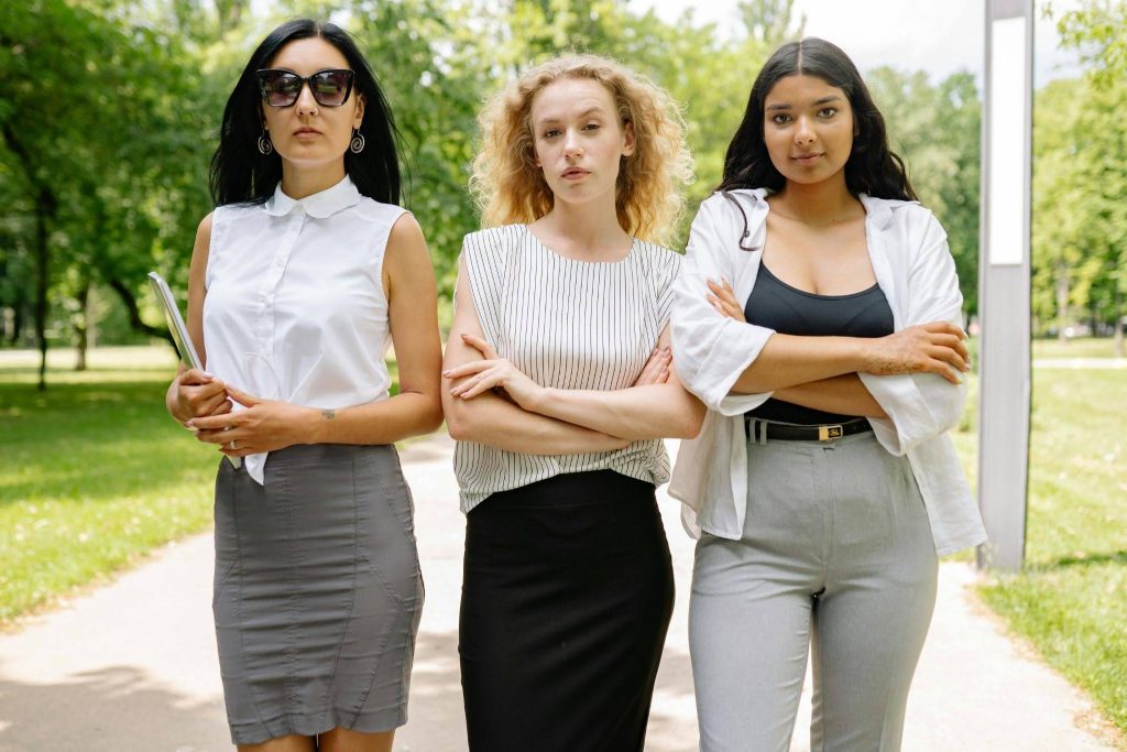 Three women standing outdoors with arms crossed
