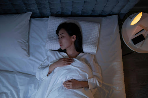 Woman lying awake in bed at night with eyes closed, struggling to sleep