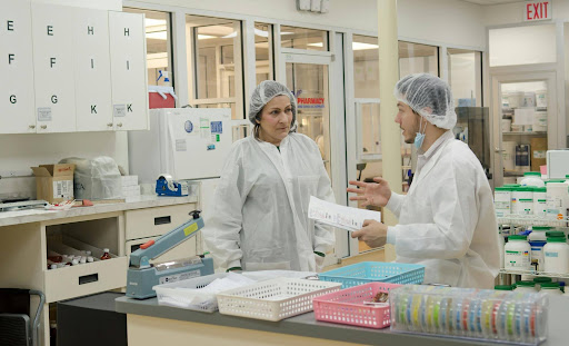  Laboratory technicians working on individualized medication compounds in a pharmacy setting. 